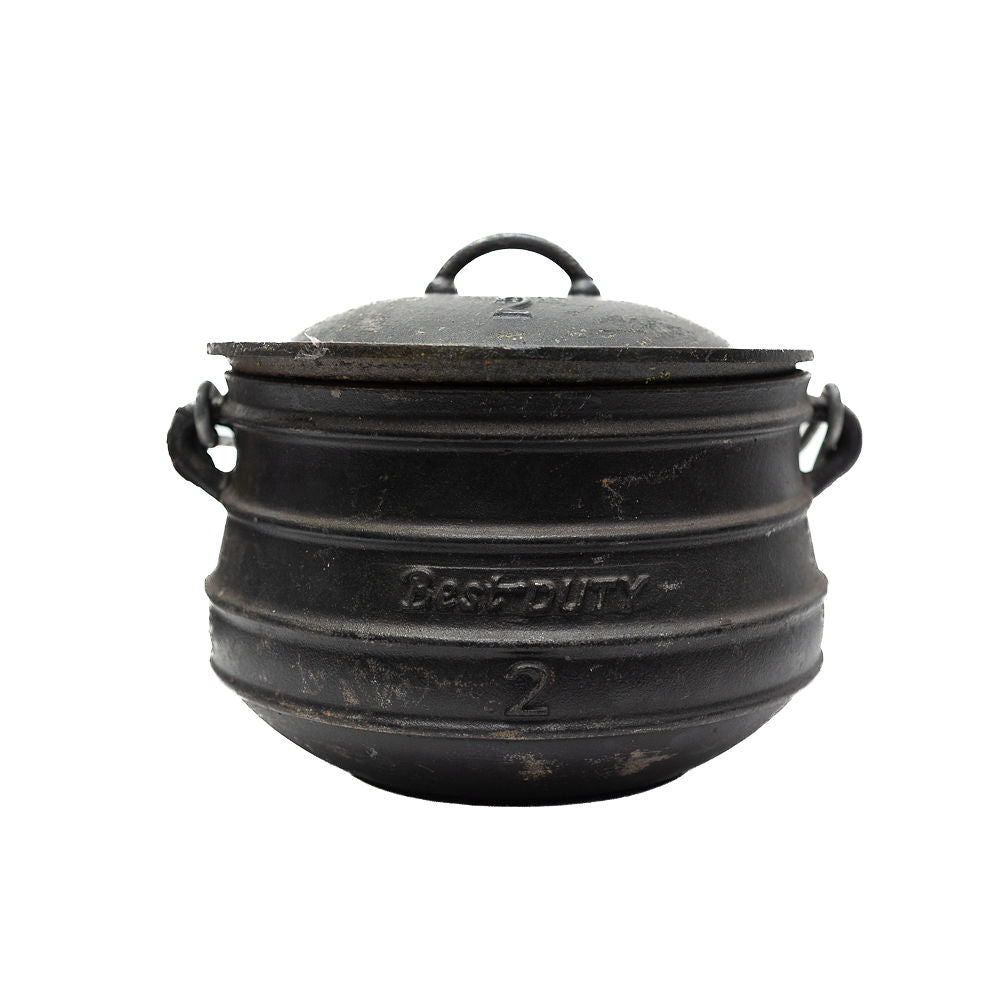 A black cast iron flat bottom potjies and a lid from Biltong Direct, on a white background.
