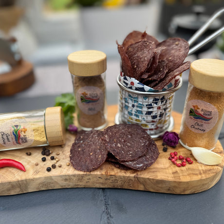Spicy Beef chips (Wieletjies) from Biltong Direct with seasoning bottles on a wooden board