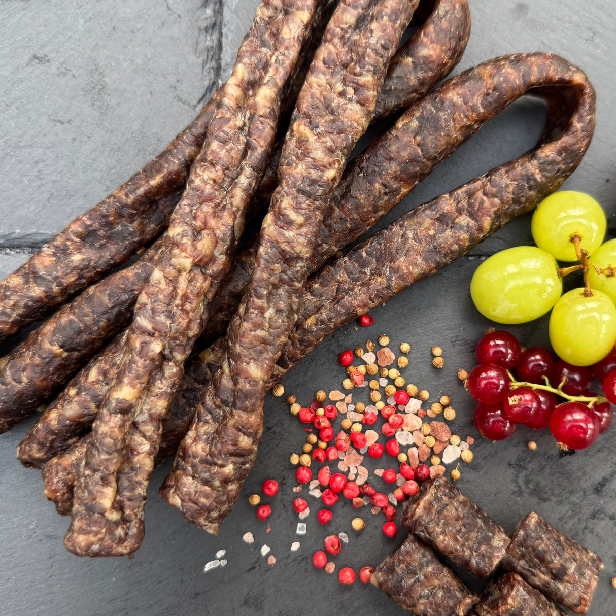 Traditional Droewors or drywors, a dried sausage from Biltong Direct with small fruits and spices on a dark surface