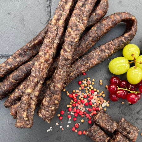 Traditional Droewors or drywors, a dried sausage from Biltong Direct with small fruits and spices on a dark surface