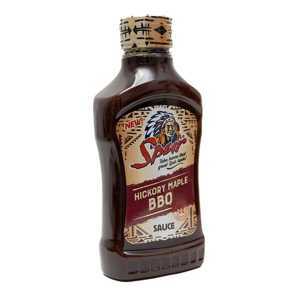 A bottle of Spur Hickory Maple BBQ Sauce from Biltong Direct with a label showing the brand logo, the type of sauce, and a description of 'All new'. The sauce is in a clear bottle with a cork top.