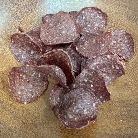 A pile of beef crisps (droewors wheels) from Biltong Direct on a wooden surface.