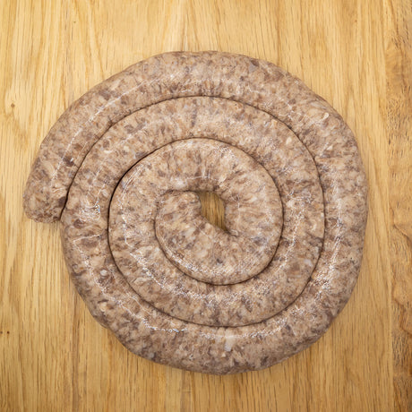 A large coil of pork-free Boerewors from Biltong Direct  made with lamb and beef, displayed on a wooden surface.