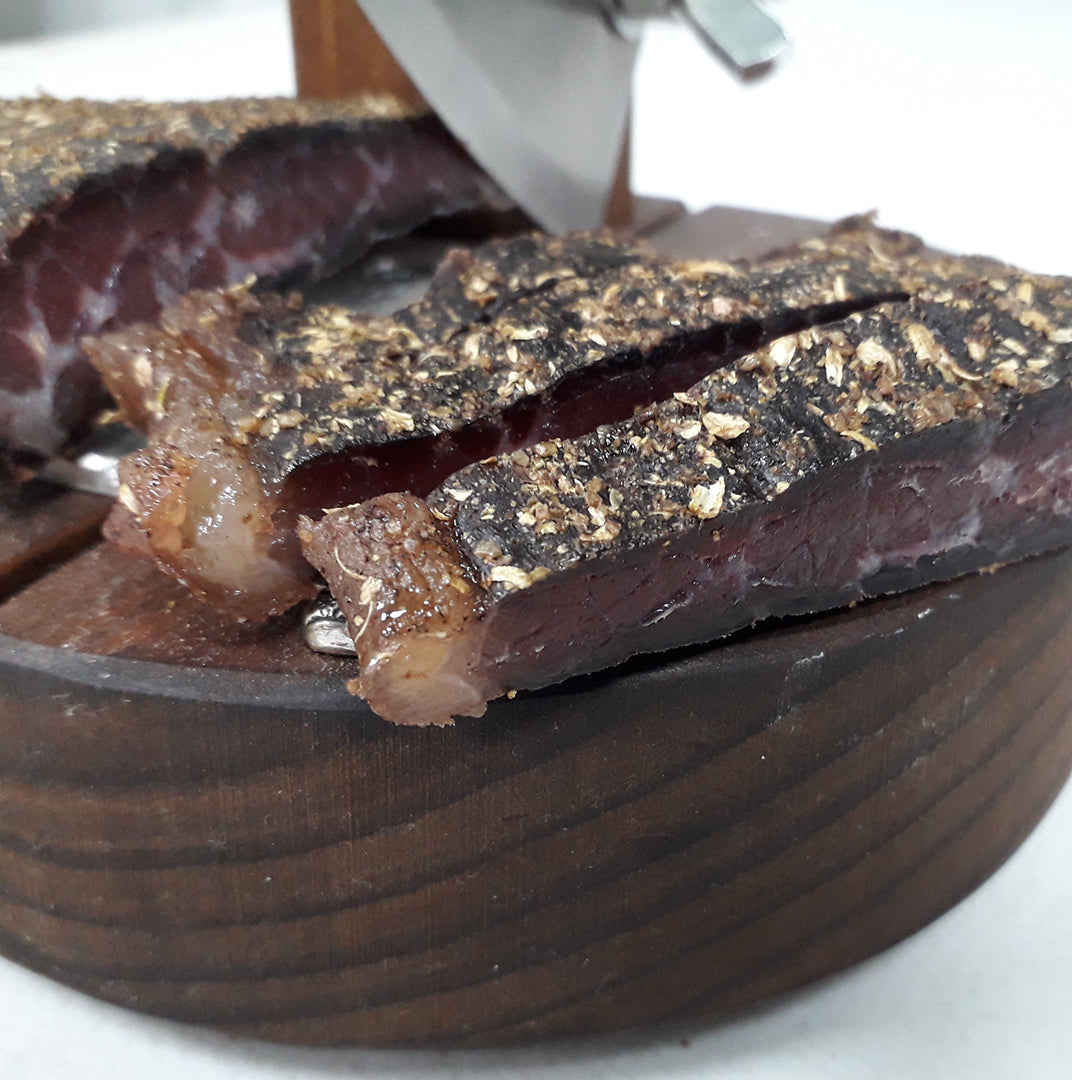Sliced biltong from Biltong Direct on a wooden board, showcasing the meat's texture and seasoning.