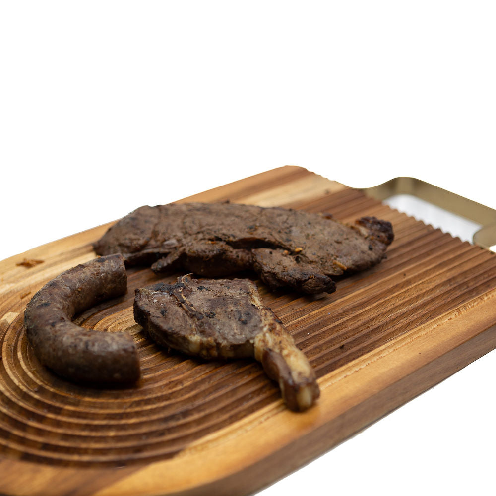 Cooked braai pack boerewors, lamb chop and a steak from Biltong Direct on a wooden board