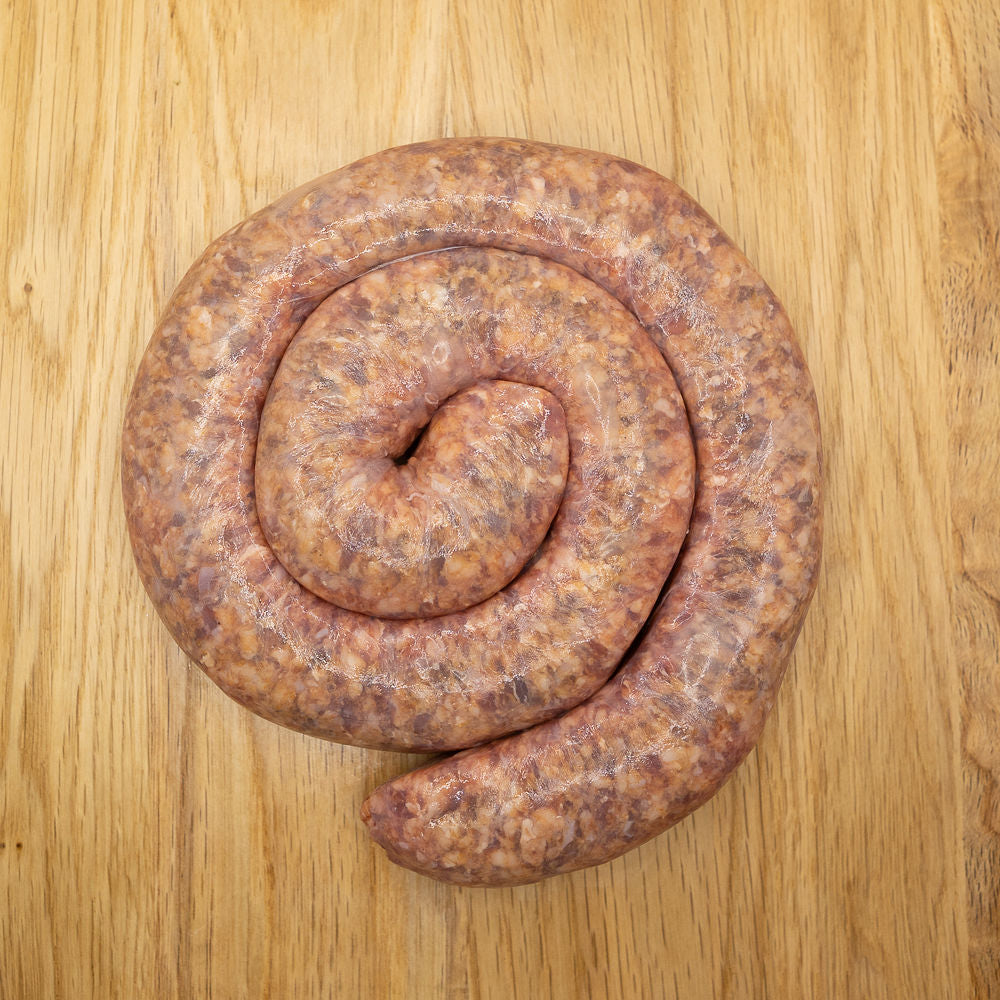A coil of raw Chakalaka Boerewors sausage from Biltong Direct laid out on a wooden surface.