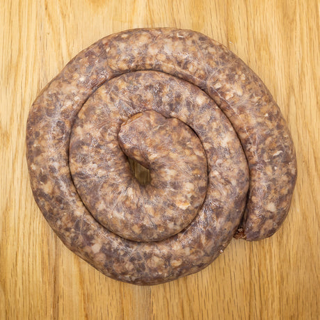 A coil of raw chilli Boerewors sausage from Biltong Direct laid out on a wooden surface.