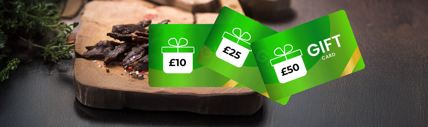 Three green gift cards from Biltong Direct with different values on a wooden surface.