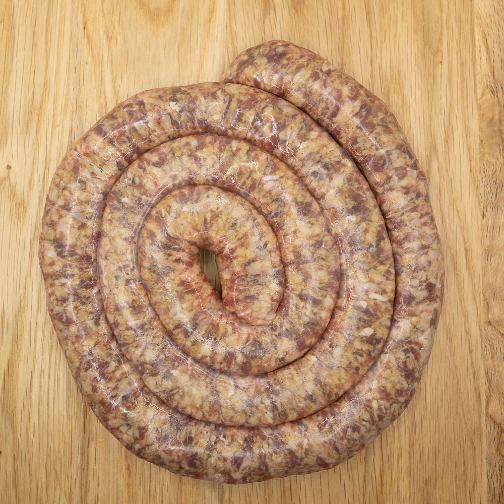 A coiled Boerewors sausage, also known as Boerewors - SOSATIE-MINIWORS from Biltong Direct, on a wooden surface.
