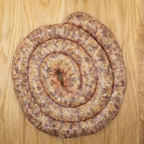 A coiled Boerewors sausage, also known as Boerewors - SOSATIE-MINIWORS from Biltong Direct, on a wooden surface.