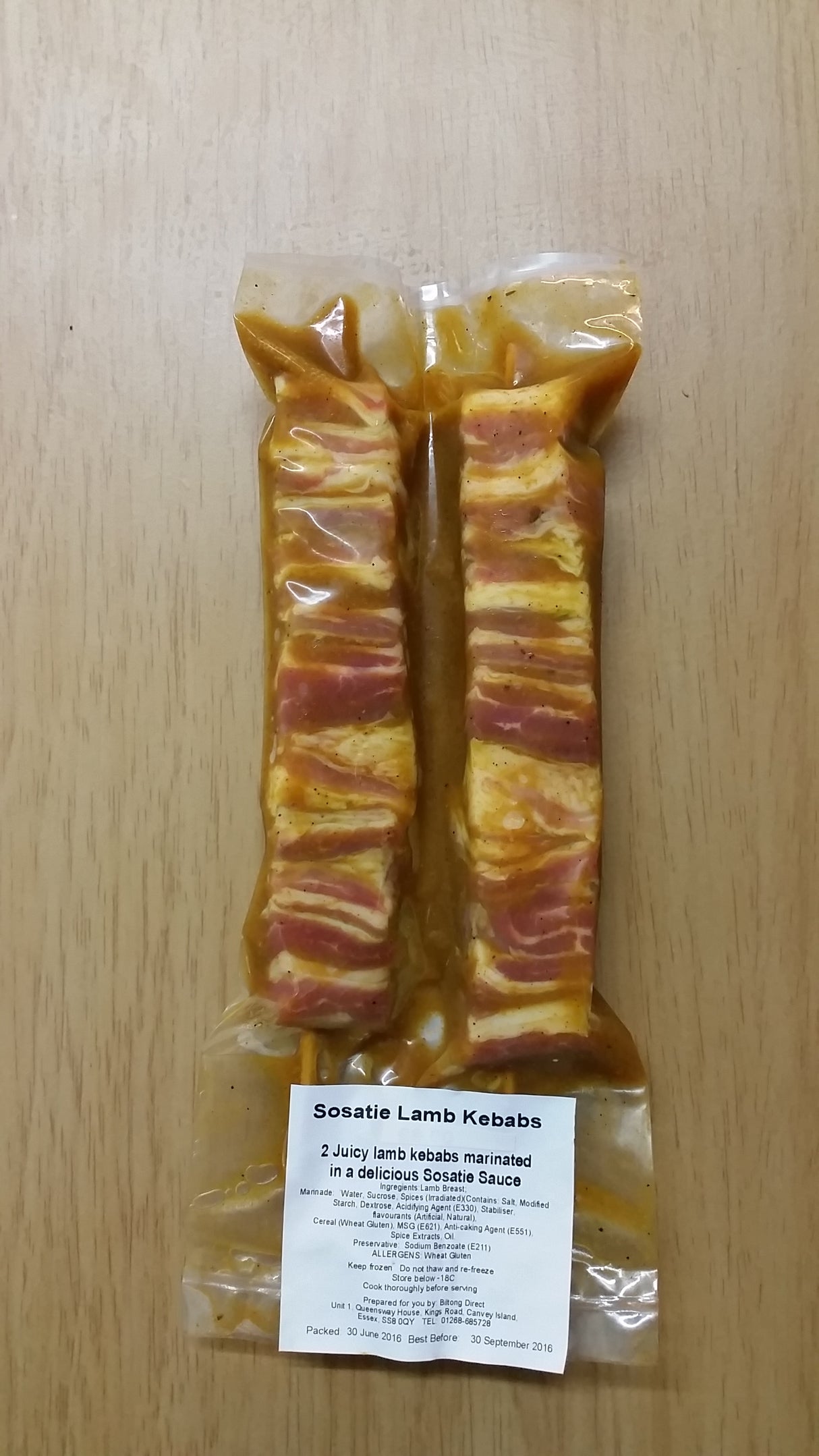 Pack of two wrapped sosaties lamb kebabs from Biltong Direct on a wooden surface, with a label showing product details.