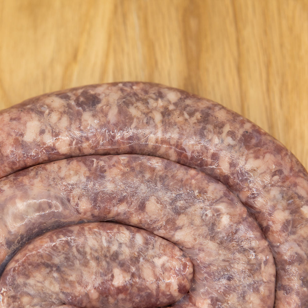 Close up of a coil of boerewors sausage from Biltong Direct on a wooden surface.