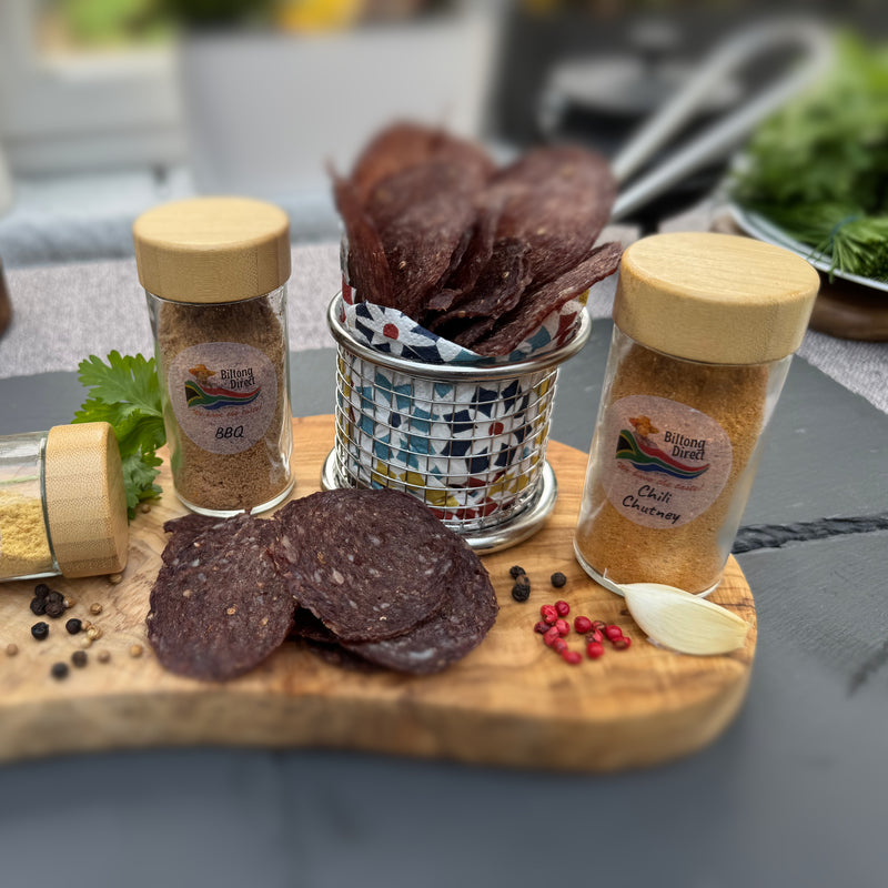 Spicy Beef chips (Wieletjies) from Biltong Direct with seasoning bottles on a wooden board