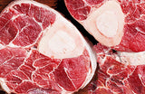 Raw beef shin cuts from Biltong Direct with visible marbling on a wooden surface.