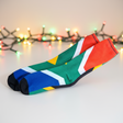 Colorful socks with a pattern resembling the South African flag on a light background with blurred lights.